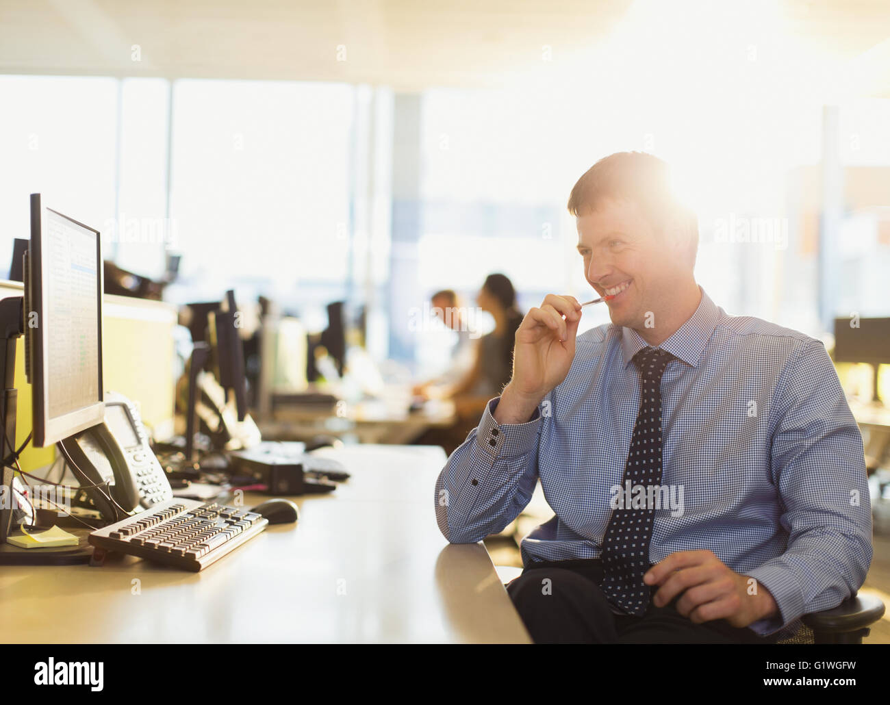 Lächelnde Geschäftsmann am Computer in sonnigen Büro Stockfoto