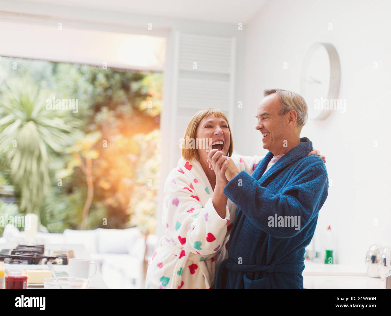 Älteres Paar im Bademantel zu Hause tanzen lachen Stockfoto