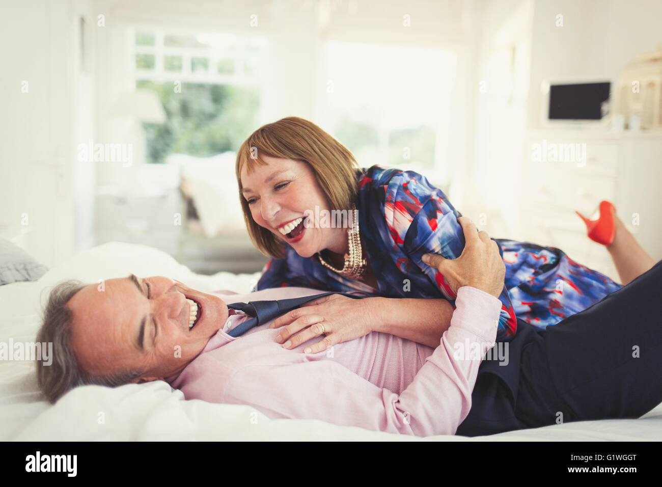 Gut gekleidete älteres paar lachend auf Bett Stockfoto