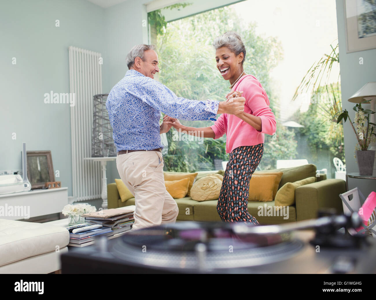 Spielerische Reife Paare tanzen im Wohnzimmer Stockfoto