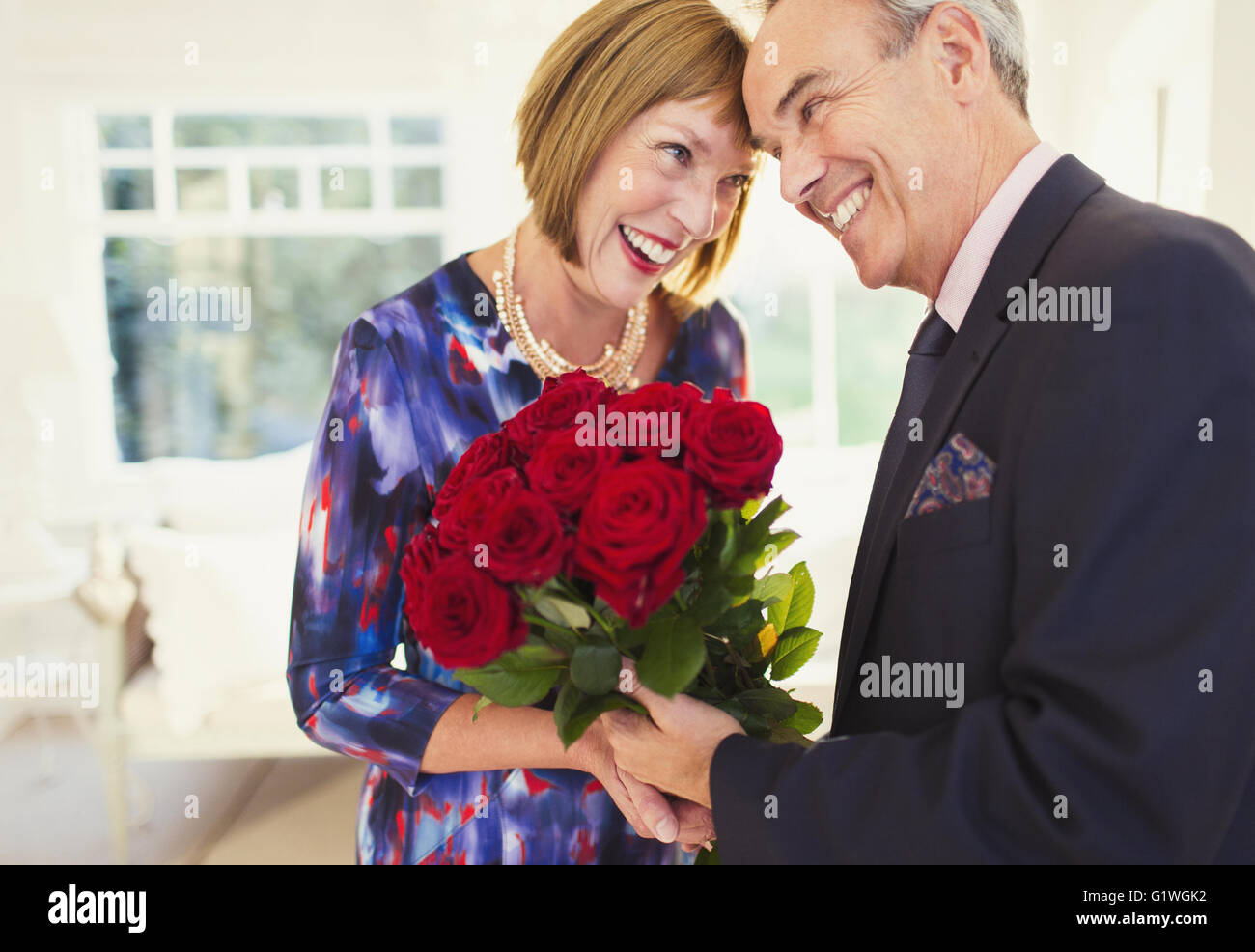 Liebevolle wohlgekleidete älteres Paar mit rose bouquet Stockfoto