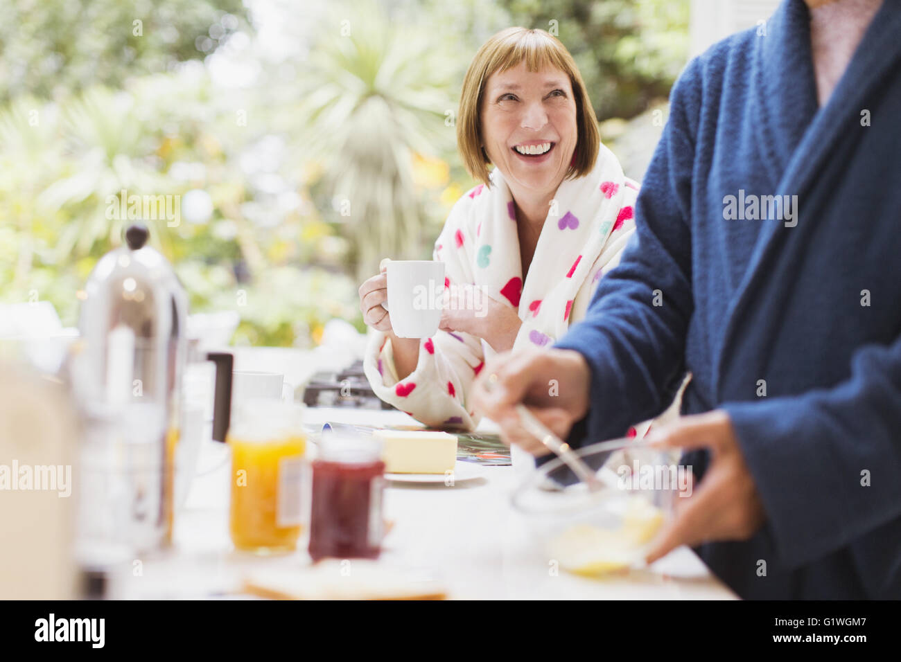 Lächelnd Reife Frau Kaffeetrinken im Bademantel beim Frühstück Stockfoto