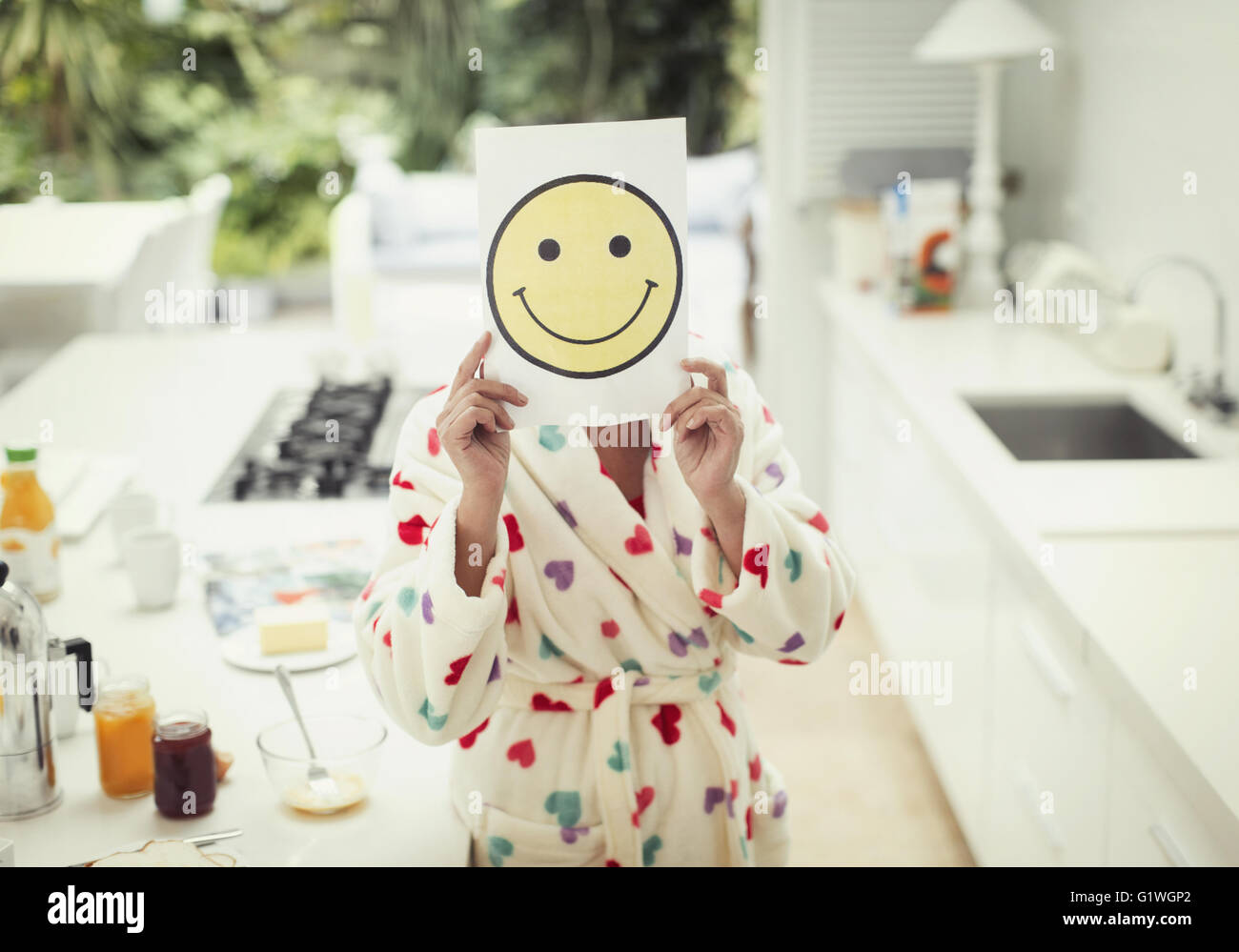 Porträt der Frau hält Smiley Gesicht Ausdruck über Gesicht in Küche Stockfoto