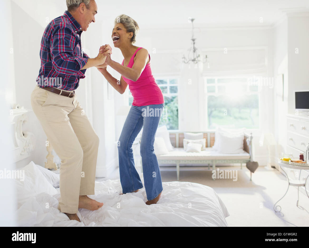 Spielerische älteres Paar auf Bett springen Stockfoto