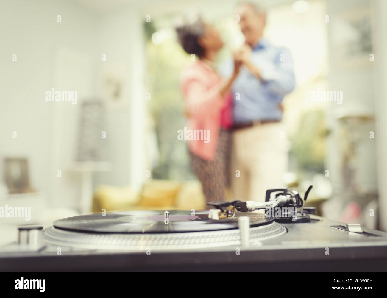 Älteres paar tanzen im Wohnzimmer hinter Plattenspieler Stockfoto