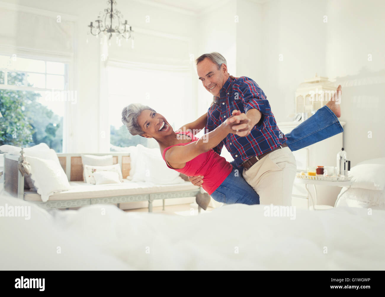 Spielerische Reife Paare tanzen im Wohnzimmer Stockfoto