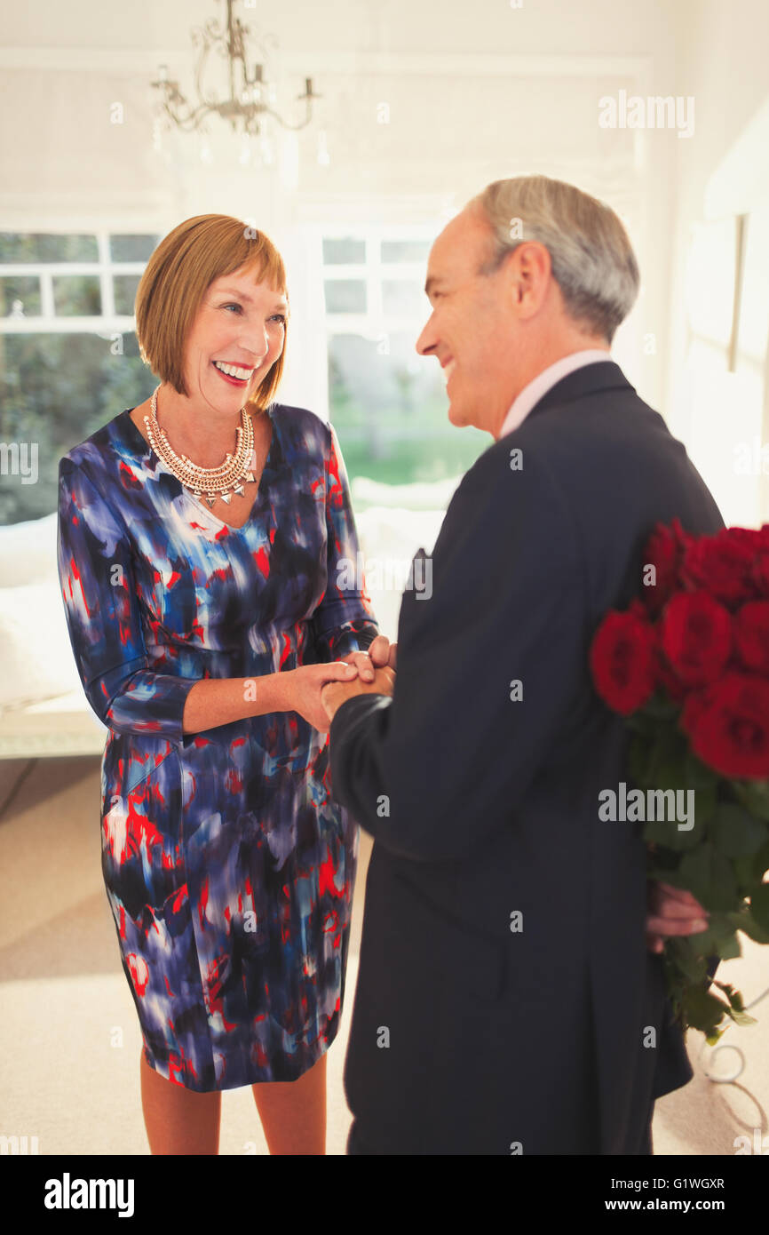 Gut gekleidete Mann überraschend Frau mit rose bouquet Stockfoto