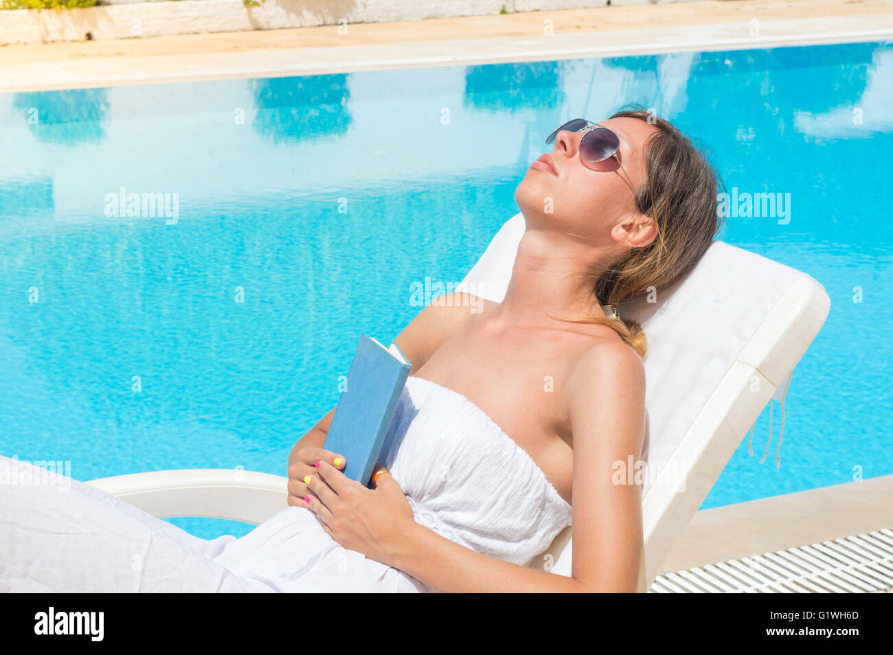 Frau mit einem Buch am Pool entspannen Stockfoto