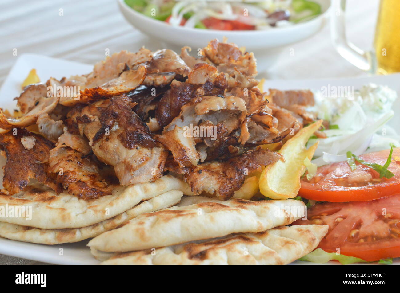 Schweinefleisch Gyros auf einem Teller mit Salat und einem Glas Bär Stockfoto