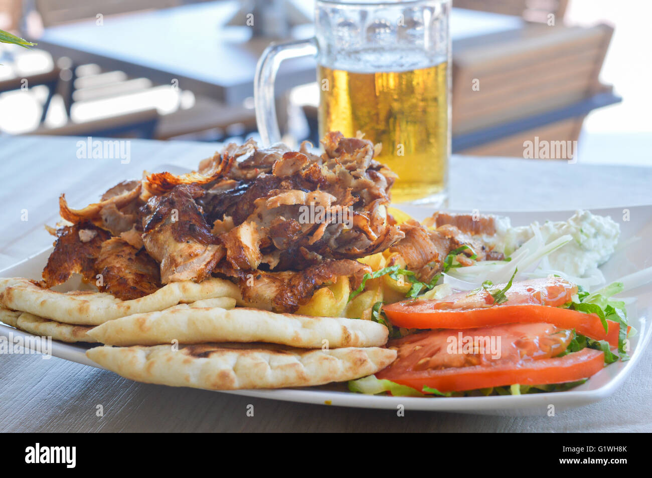 Schweinefleisch Gyros auf einem Teller mit Salat und einem Glas Bär Stockfoto