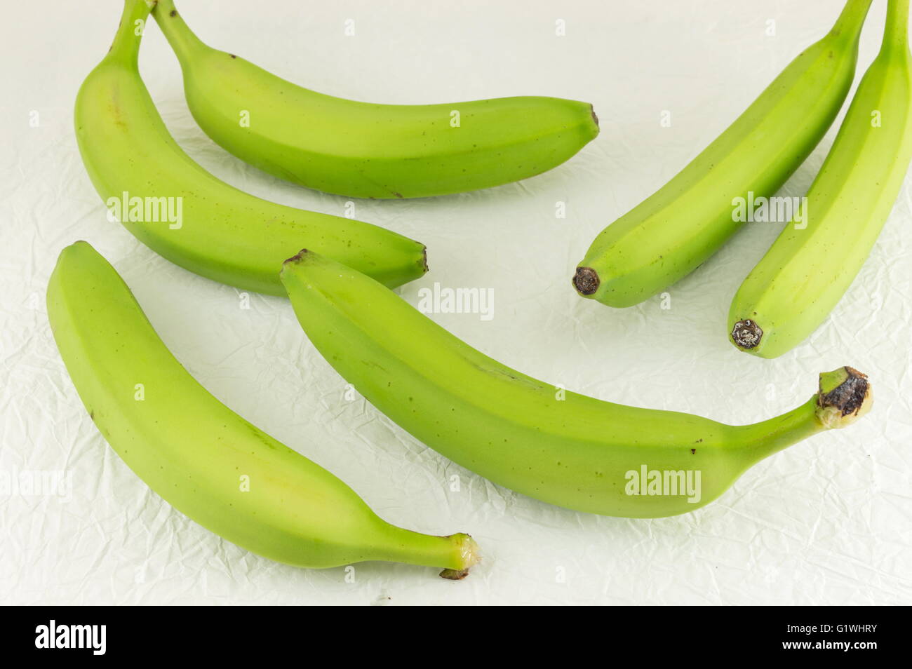 Grünen jungen Bananen auf weißen Textilien Stockfoto