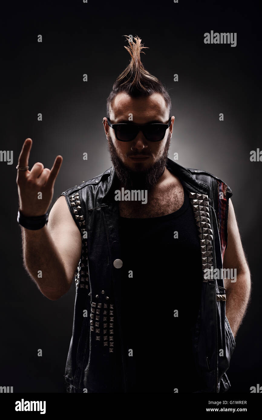 Vertikale Schuss ein machen eine Hardcore-Punk-Rocker hand Geste auf dunklem Hintergrund Stockfoto