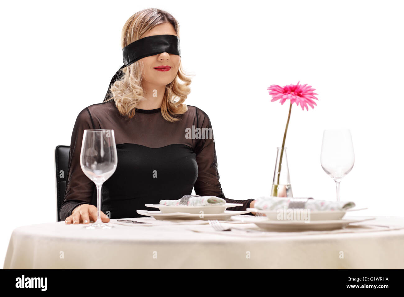 Junge Frau mit Augenbinde auf ihre Augen an einem romantischen Abendessen Tisch isoliert auf weißem Hintergrund Stockfoto
