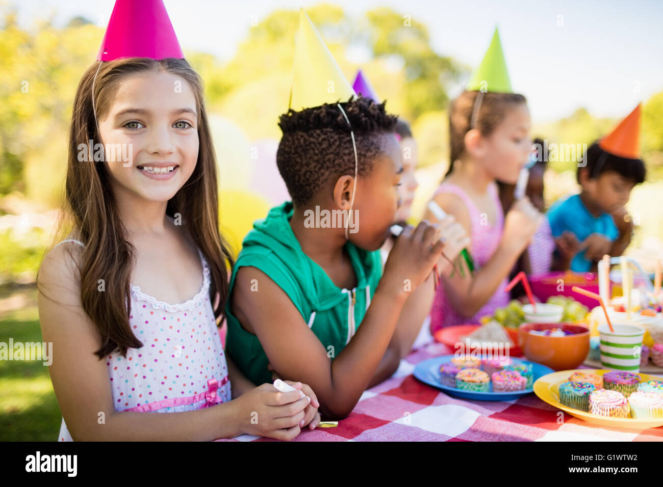 Nahaufnahme von niedlichen Mädchen lächelnd vor anderen Kindern während einer Geburtstagsfeier Stockfoto