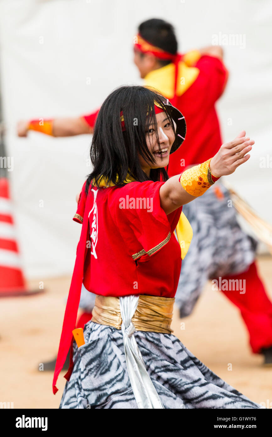 Japanische Hinokuni Yosakoi Dance Festival. Junge lächelnde Frau Tänzer tanzen im Freien und das Tragen der roten yukata Jacke. Ein Teil der Mannschaft. Close Up. Stockfoto