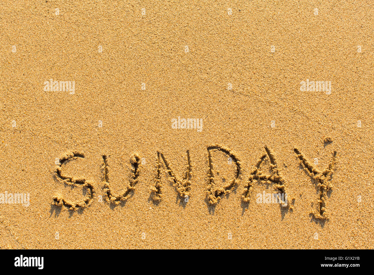 Sonntag - Inschrift von Hand auf einen Licht-goldenen Sandstrand. Stockfoto