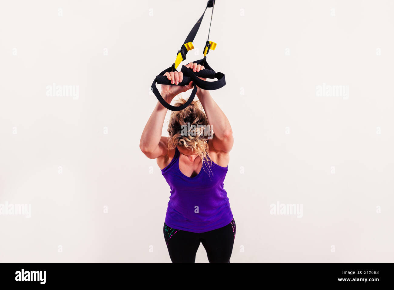 Eine junge Frau tut Körpergewicht Übungen mit Riemen Stockfoto