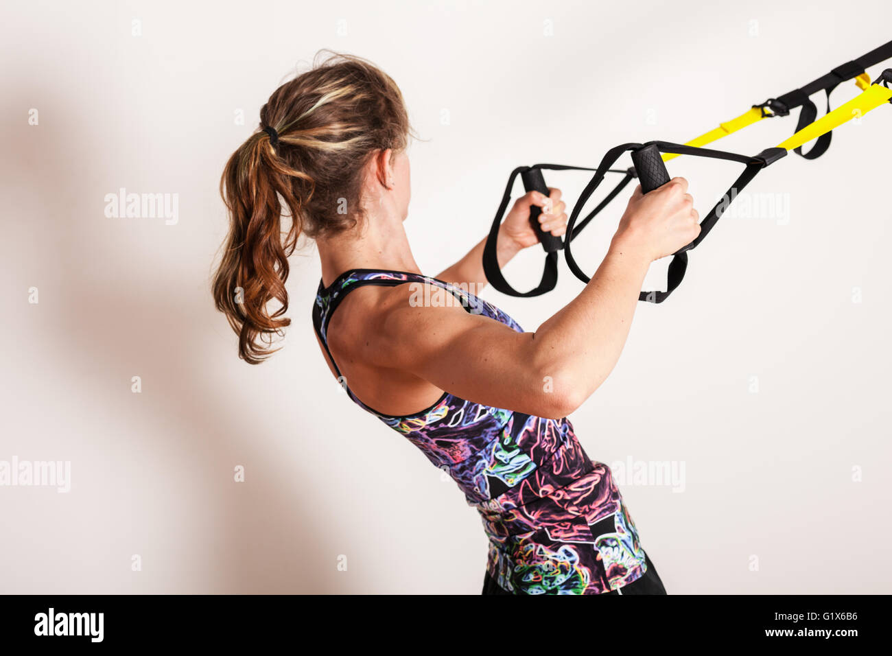 Eine junge Frau tut Körpergewicht Zeilen mit Riemen Stockfoto