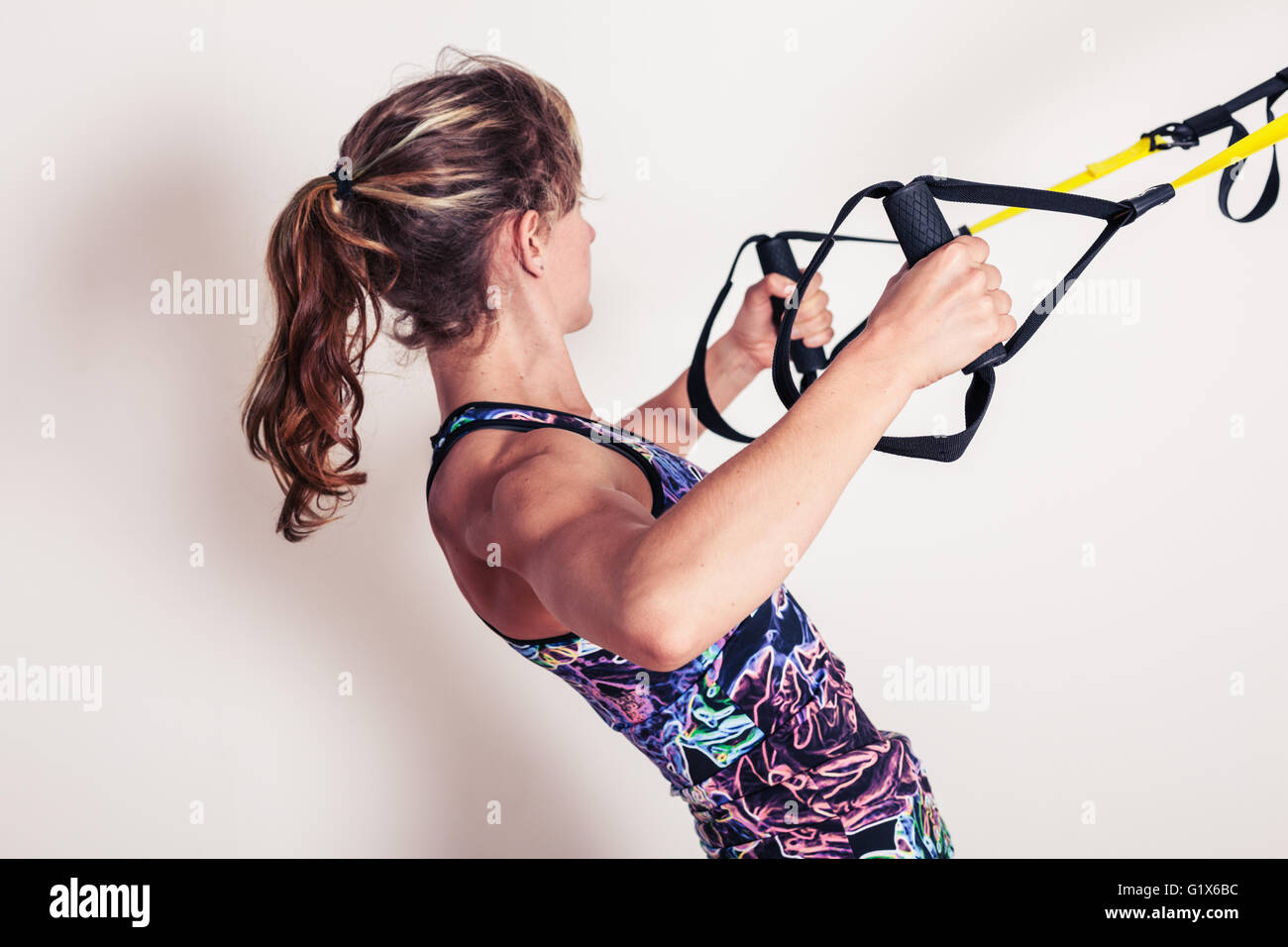 Eine junge Frau tut Körpergewicht Zeilen mit Riemen Stockfoto