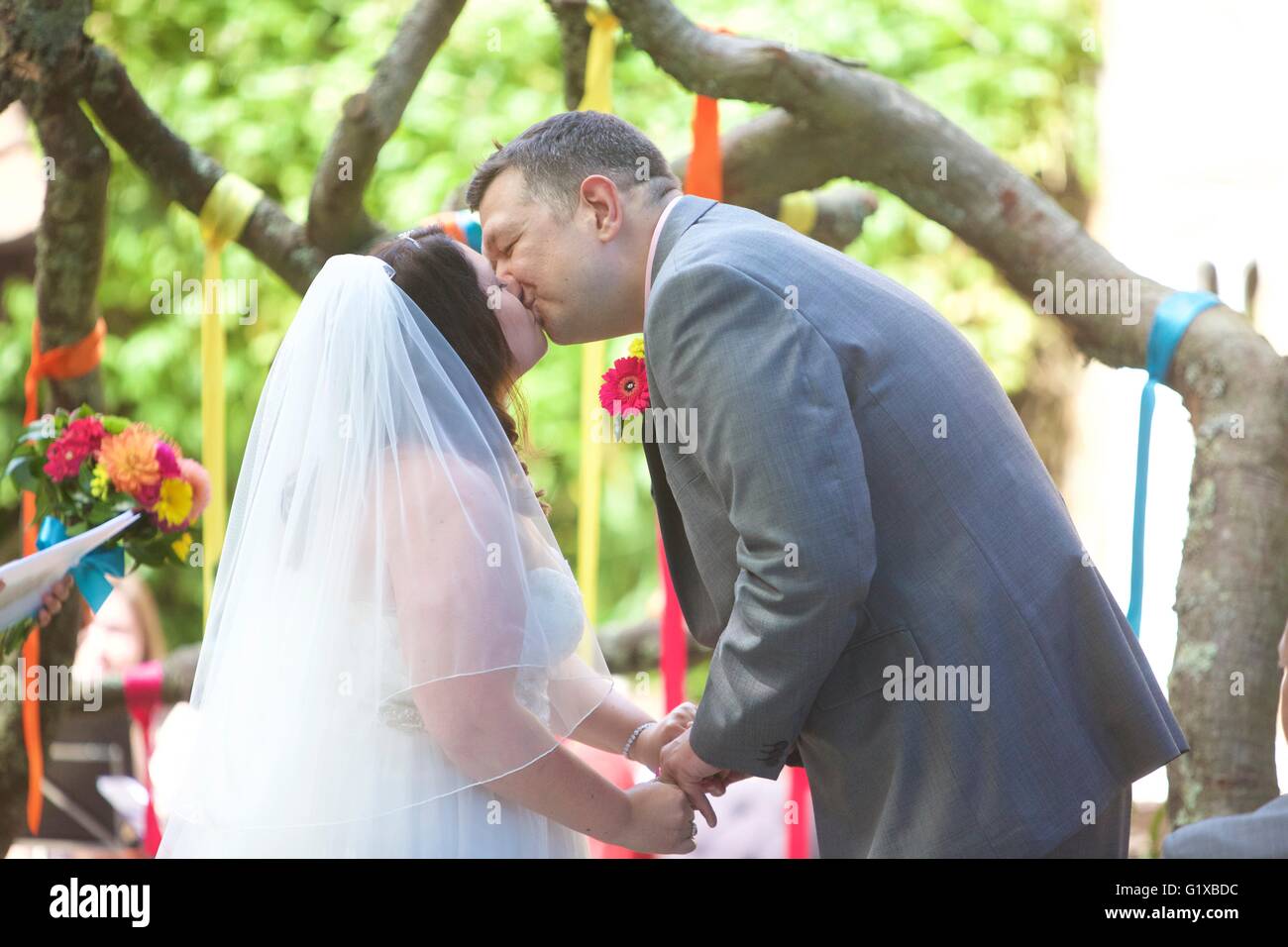 Braut und Bräutigam küssen nach ihrem Gelübde, die bei einem open air Hochzeit sagen. Stockfoto