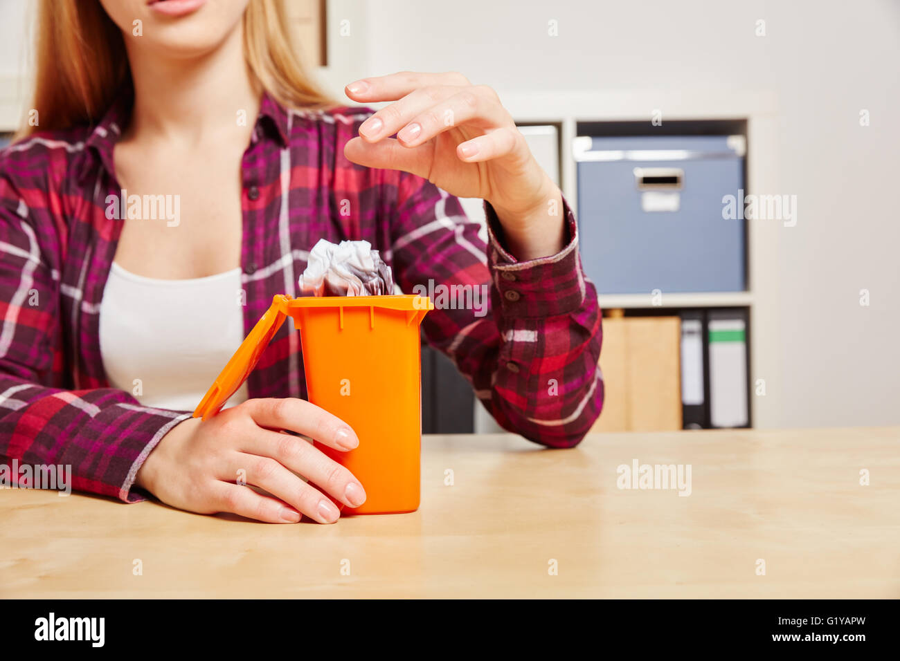 Frau wirft Papier in einen kleinen Mülleimer auf ihren Schreibtisch Stockfoto