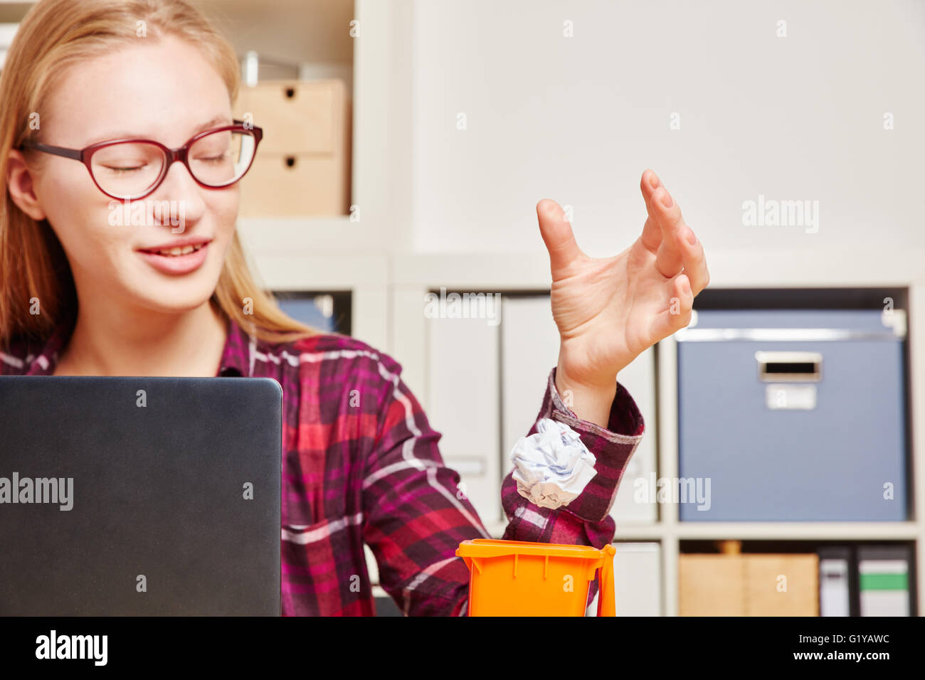 Frau im Büro verfügt über zerknittertes Papier in eine kleine Mülltonne Stockfoto