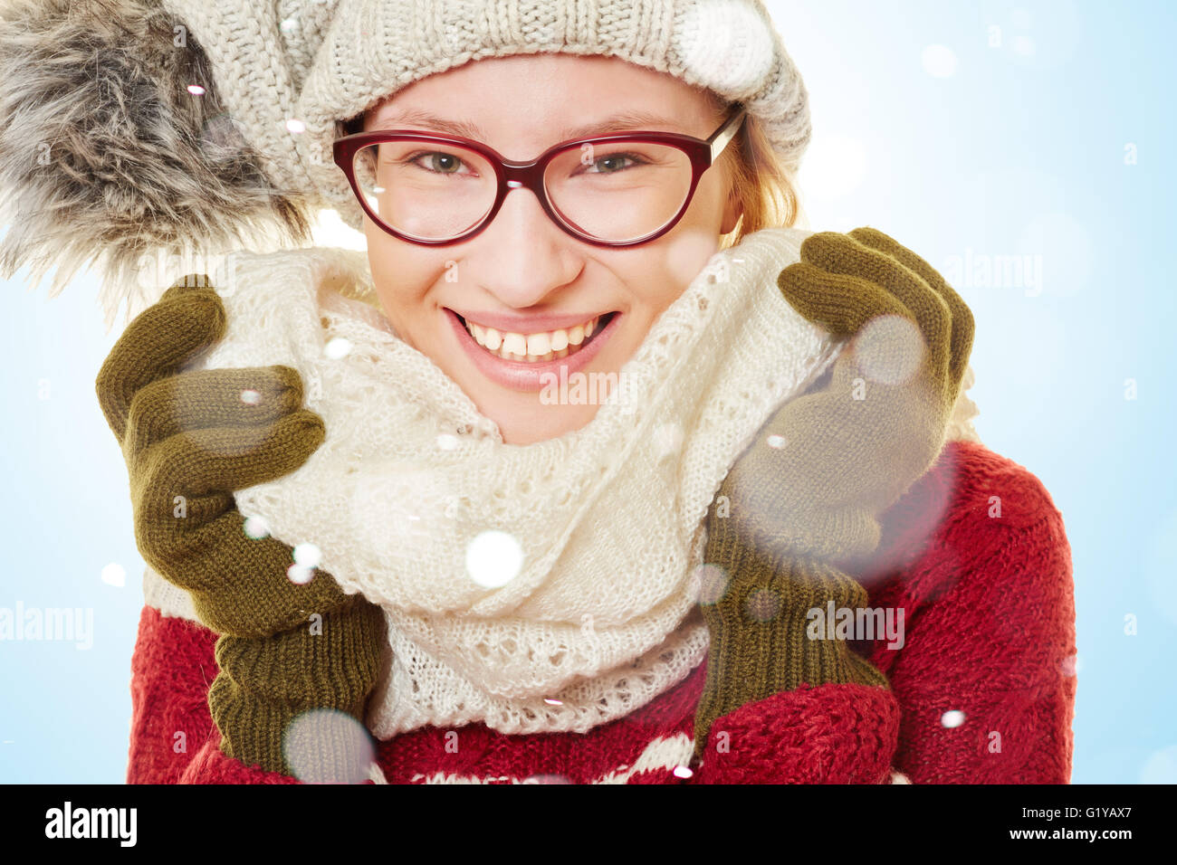 Lächelnde junge Frau im Schnee im Winter tragen Winterkleidung Stockfoto