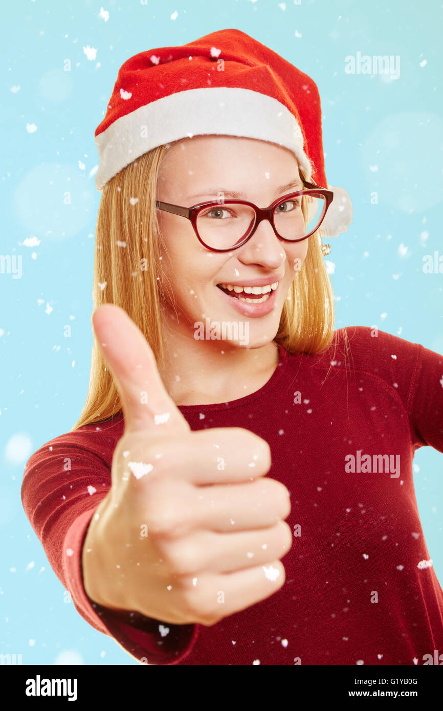 Fröhliche Frau im Schnee zu Weihnachten mit ihrem Daumen nach oben Stockfoto