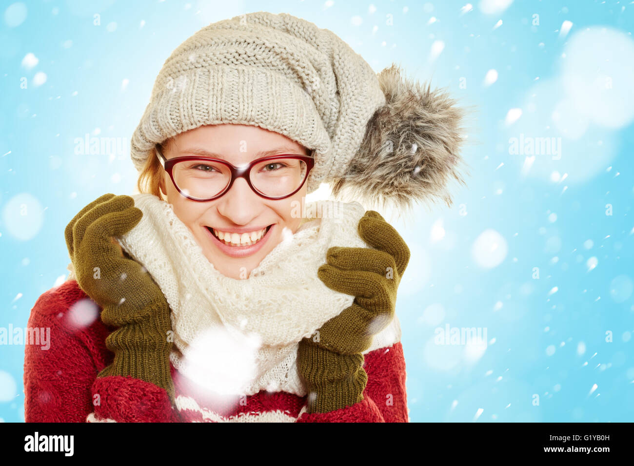 Lächelnde Frau im Schnee im Winter mit Winterkleidung Stockfoto