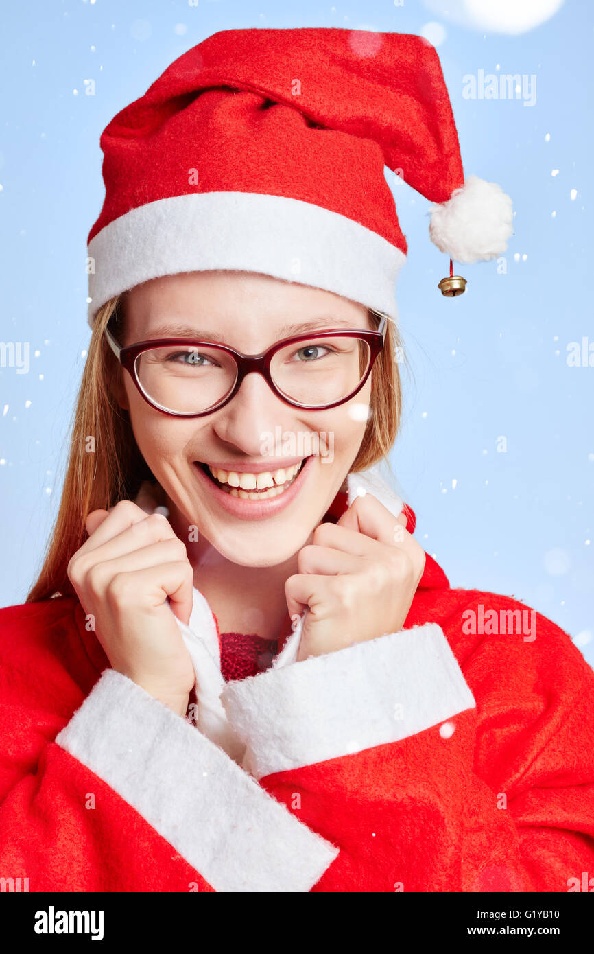 Lächelnde Frau im Schnee mit einer roten Kappe für Weihnachten als Weihnachtsmann verkleidet Stockfoto