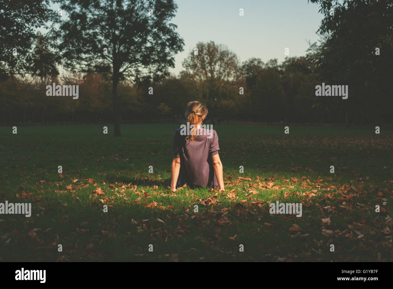 Eine junge Frau ist auf dem Rasen im Park am Abend Standortwahl. Stockfoto