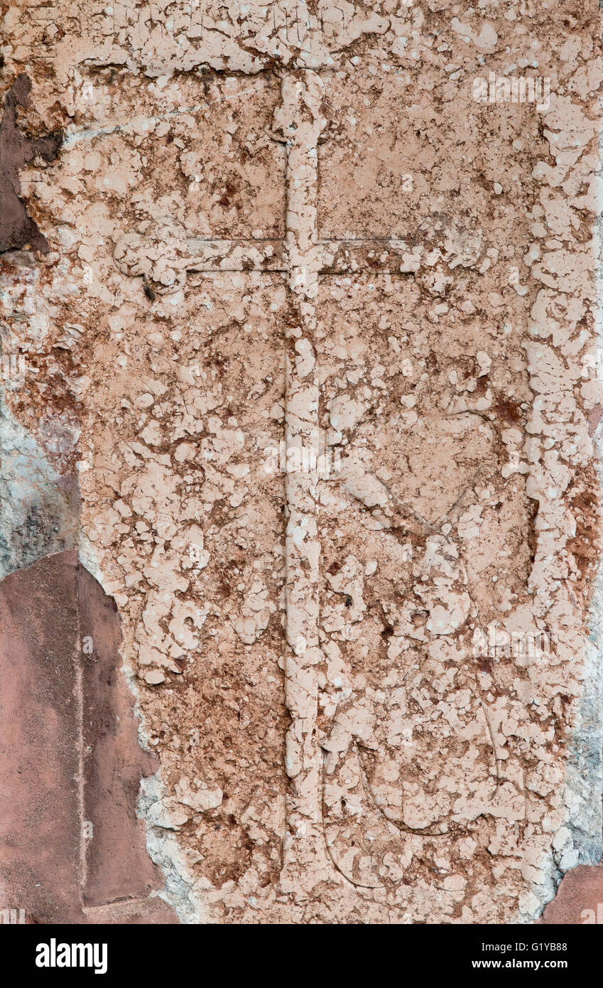 Kreuz auf Steinmauer Stockfoto