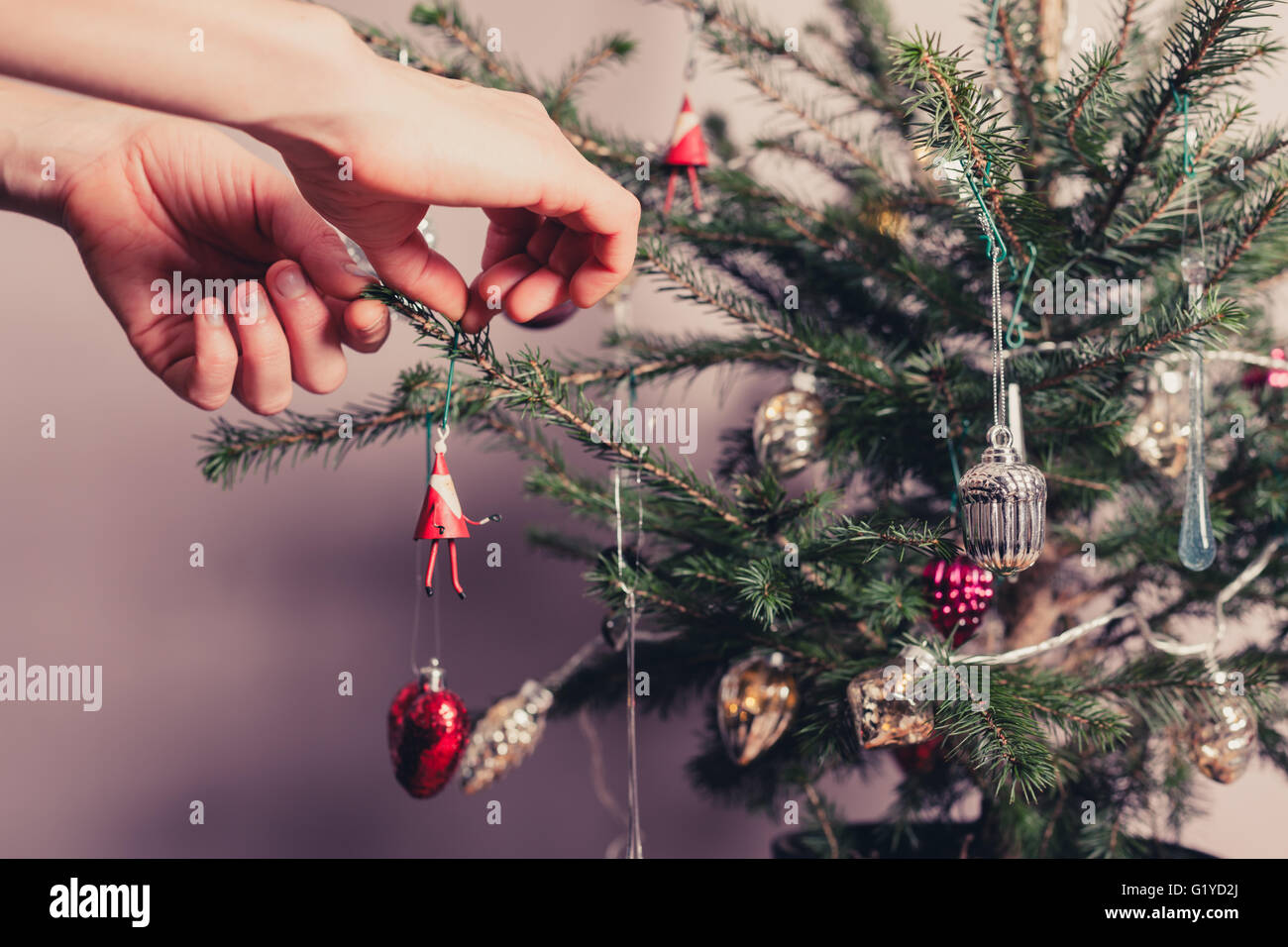 Hände, die einen Weihnachtsbaum mit allerlei bunten Sachen zu verzieren Stockfoto