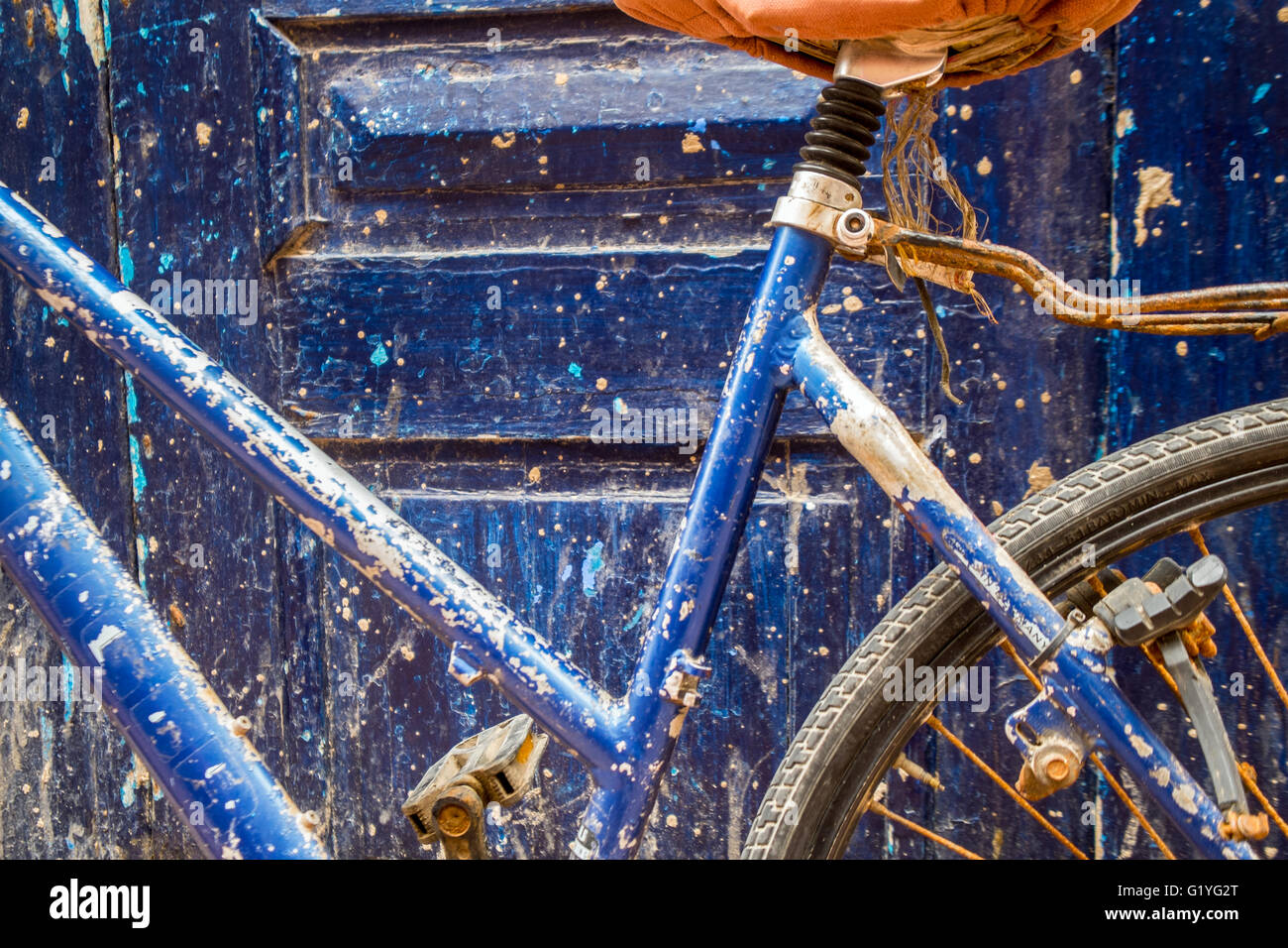 Ein blaues Fahrrad stützte sich auf eine Tür von der gleichen Farbe in Marokko Stockfoto