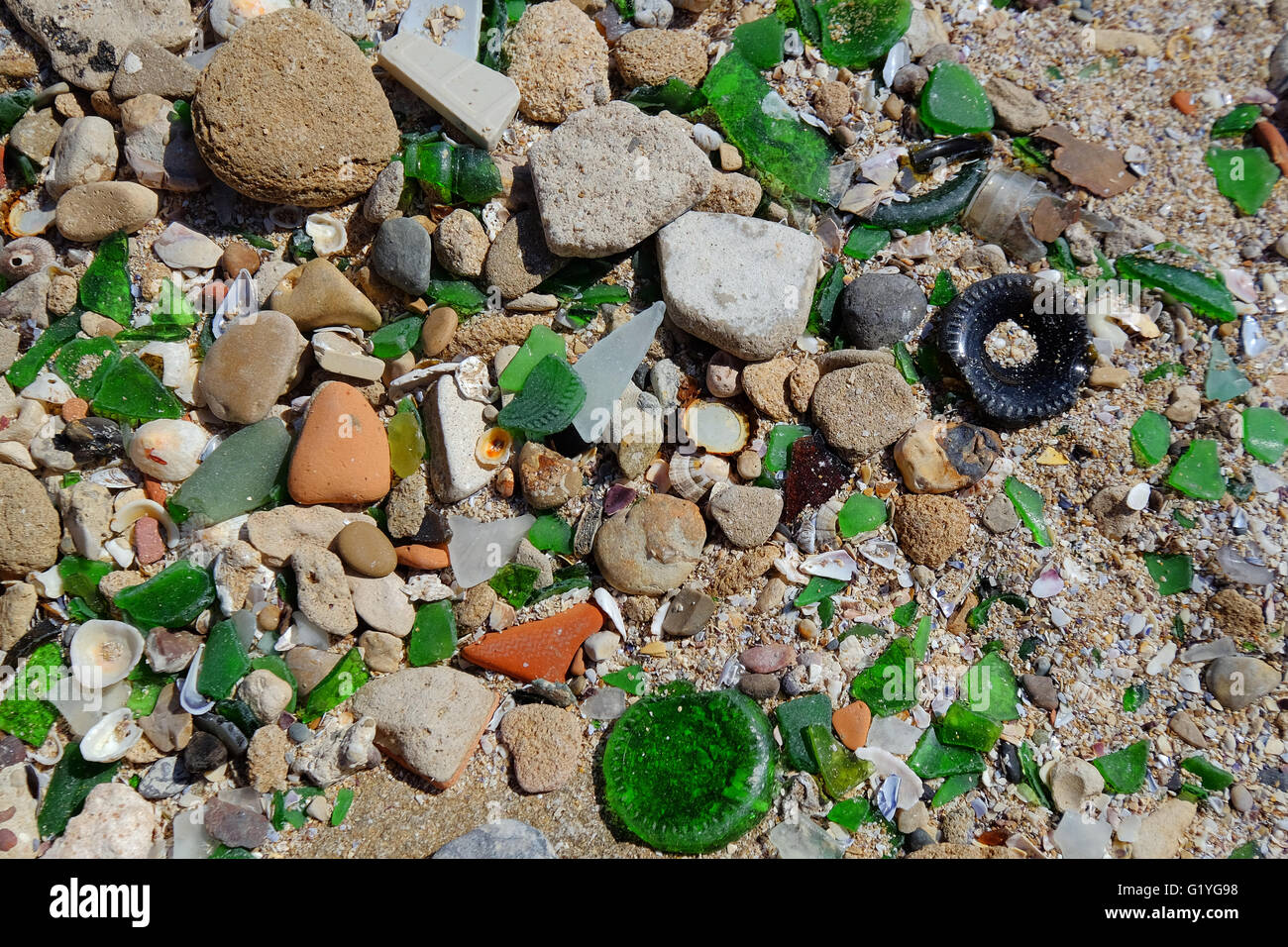 Große Mengen von zerbrochenem Glas unter die Kieselsteine am Strand an der Küste Marokkos Stockfoto