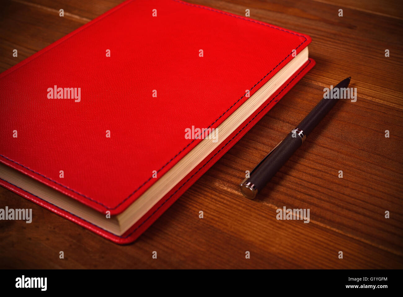 rotem Leder Tagebuch und Stift auf Schreibtisch aus Holz Stockfoto
