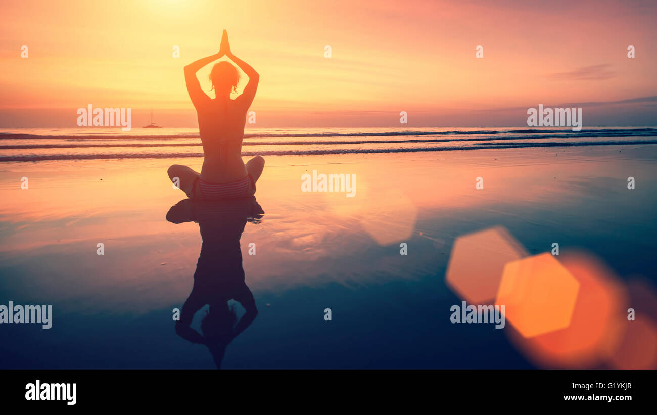 Erstaunliche Yoga Hintergrund, Silhouette der Frau am Strand bei Sonnenuntergang, Meditation und Achtsamkeit. Stockfoto