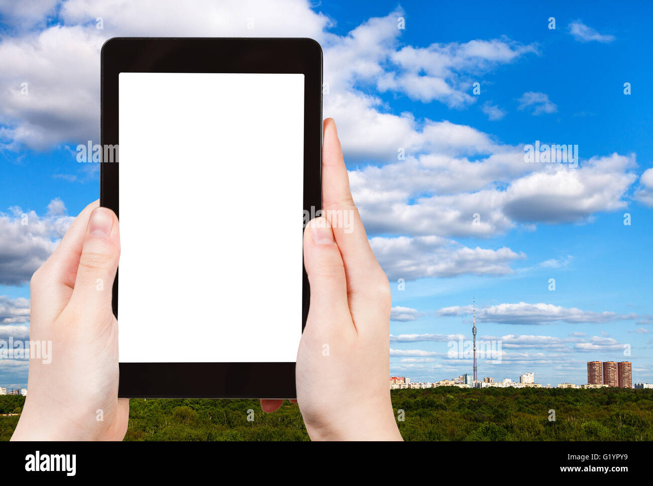 Saison Konzept - Tourist fotografiert blauen Himmel mit weißen Wolken über grünen Sommer Wald und Stadt am Horizont auf Tablet-pc mit c Stockfoto