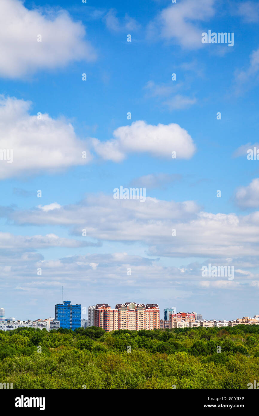 Appartementhäuser und grünen Wald unter bewölkten blauen Himmel im Sommertag Stockfoto
