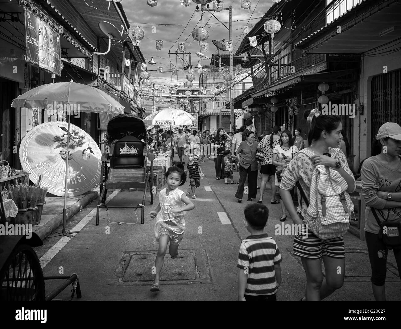 Straßenszene Thailand. Kinder spielen und Rennen durch die Menge. China Town Thailand S. E. Asien. Schwarzweiß-Fotografie Stockfoto
