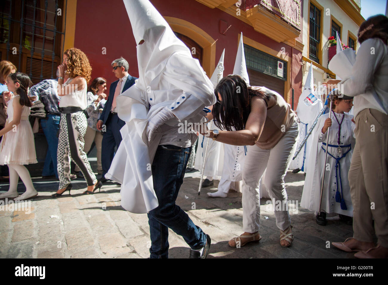 Ein Verwandter von einem "Nazareno" der Bruderschaft namens "La Paz" ordnen Sie ihre Kleidung während der Parade zur Kathedrale am Sonntag der Palmen, genannt Tag Domingo de Ramos in spanischer Sprache. Sevilla, Spanien, 13. April 2014 Stockfoto