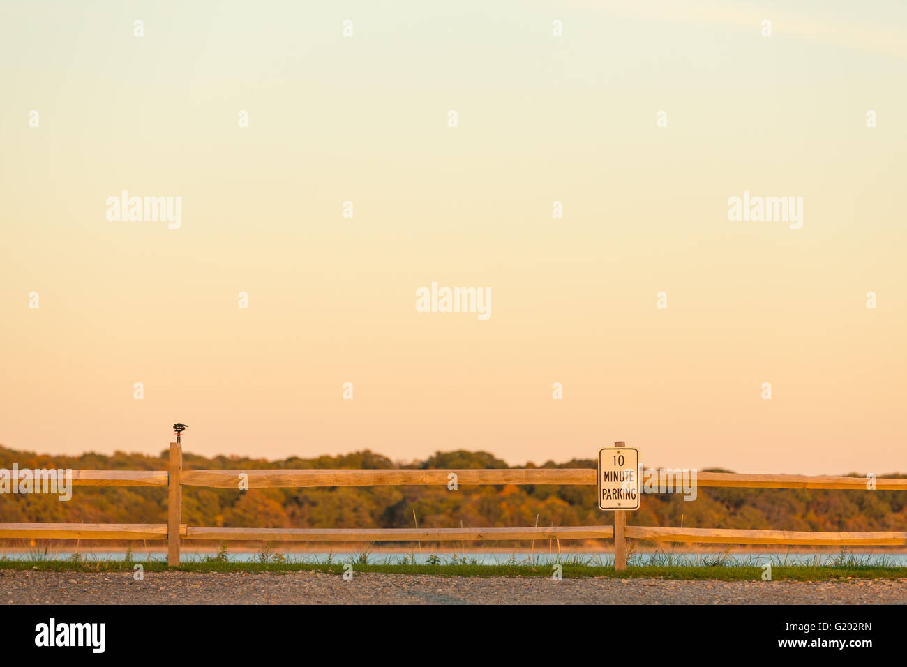 Landschaft aus Kies, Gras, Split Zaun, Bäume und 10 Minuten parken Zeichen. Stockfoto