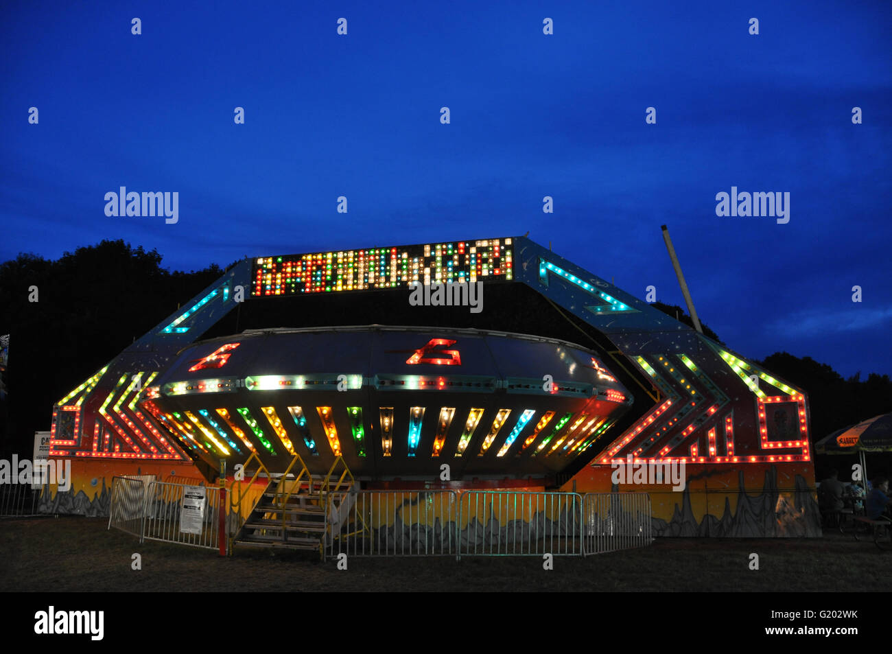 Carnival Ride in der Dämmerung mit mehreren Leuchten, sieht aus wie eine fliegende Untertasse, Sag Harbor, NY Stockfoto