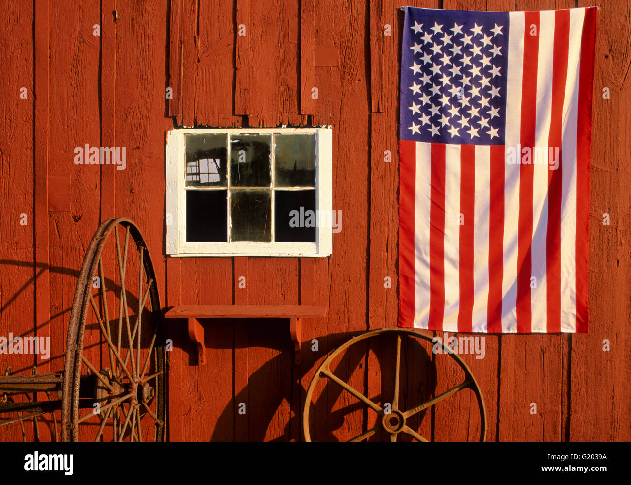 Nahaufnahme der US-Flagge auf einer roten Scheune und rostigen Rädern, New Jersey Farm, USA, US-Flagge ländliche Amerika historische Bilder koloniale US-Flagge Nahaufnahme des Frühlings Stockfoto