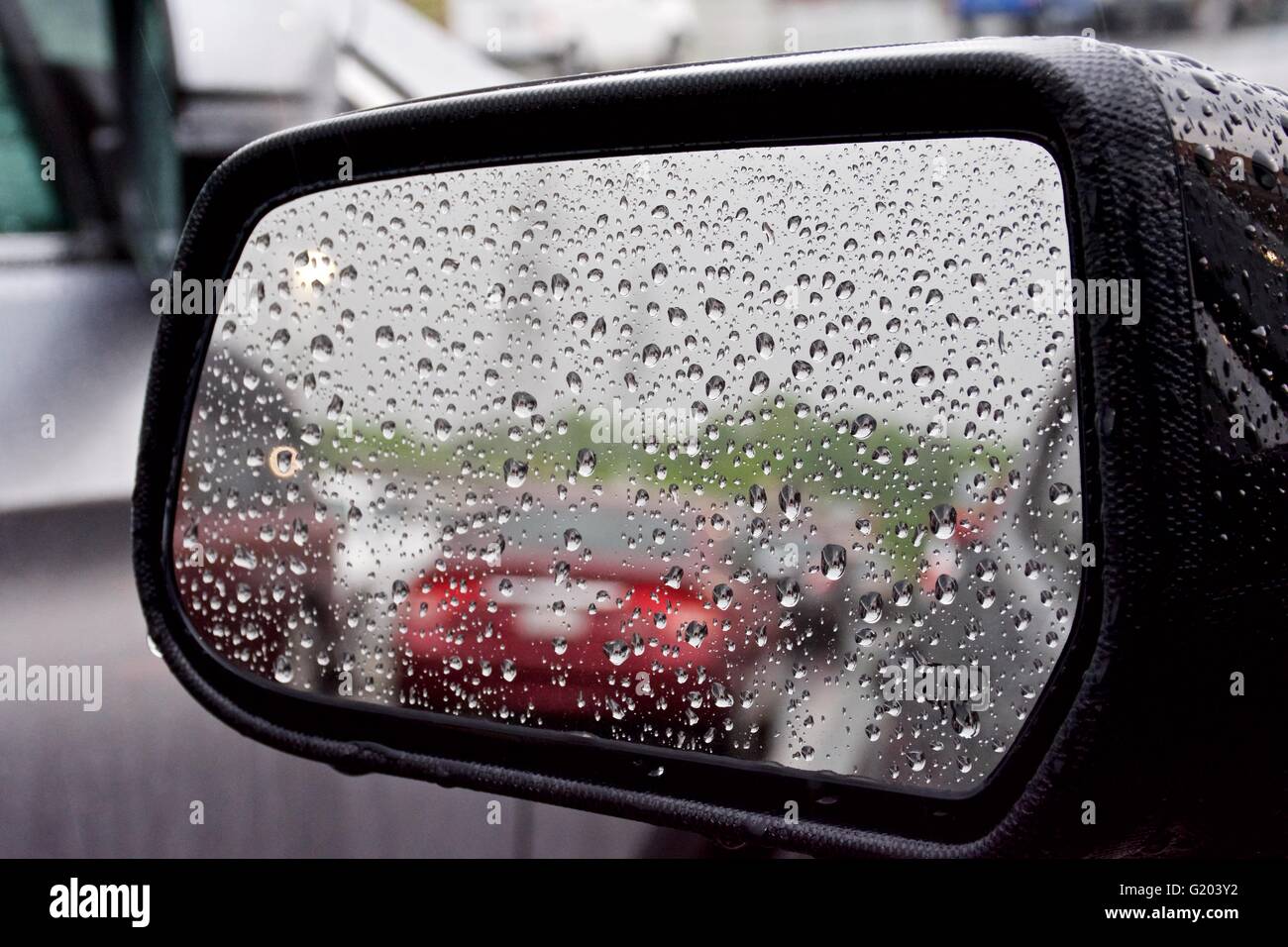 Blick durch den seitlichen Spiegel eines Autos an einem regnerischen Tag Stockfoto
