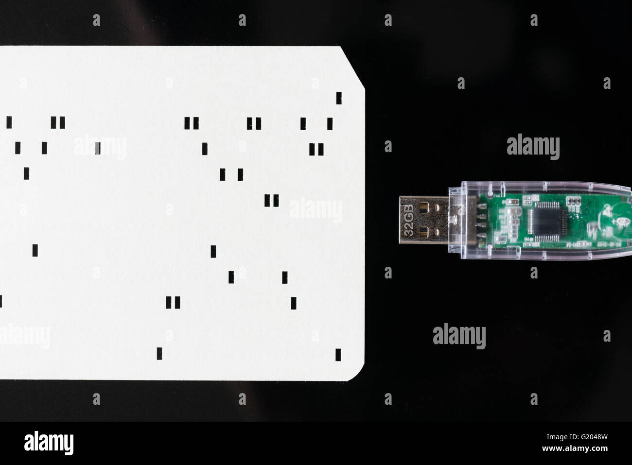 Nahaufnahme von einem modernen 32GB USB-Stick ab 2016 neben historischen frühen Computer-Lochkarte (aus ca. 1970) Stockfoto
