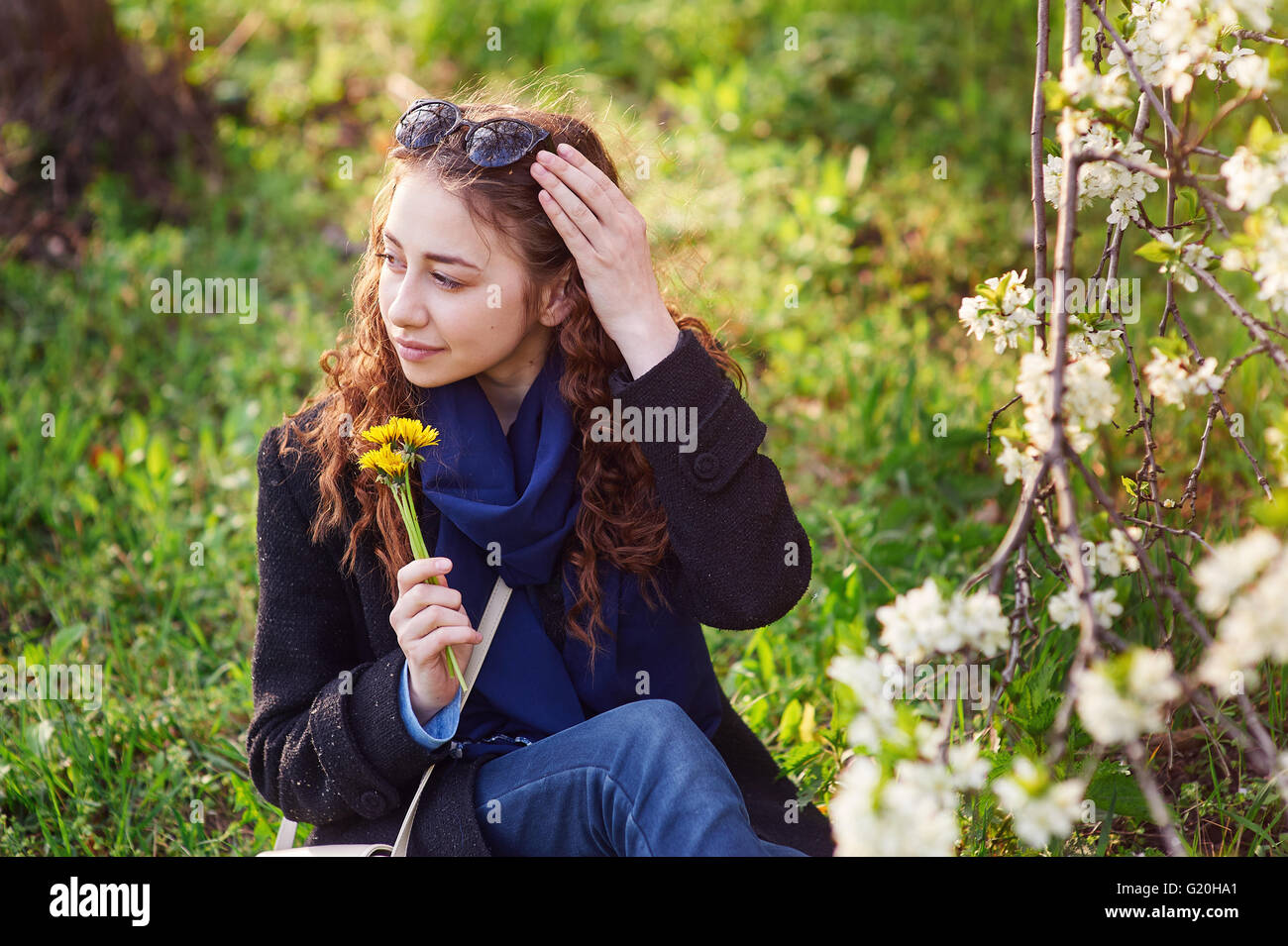 junge Frau im schwarzen Mantel zu Fuß in einer blühenden Frühlingsgarten Stockfoto