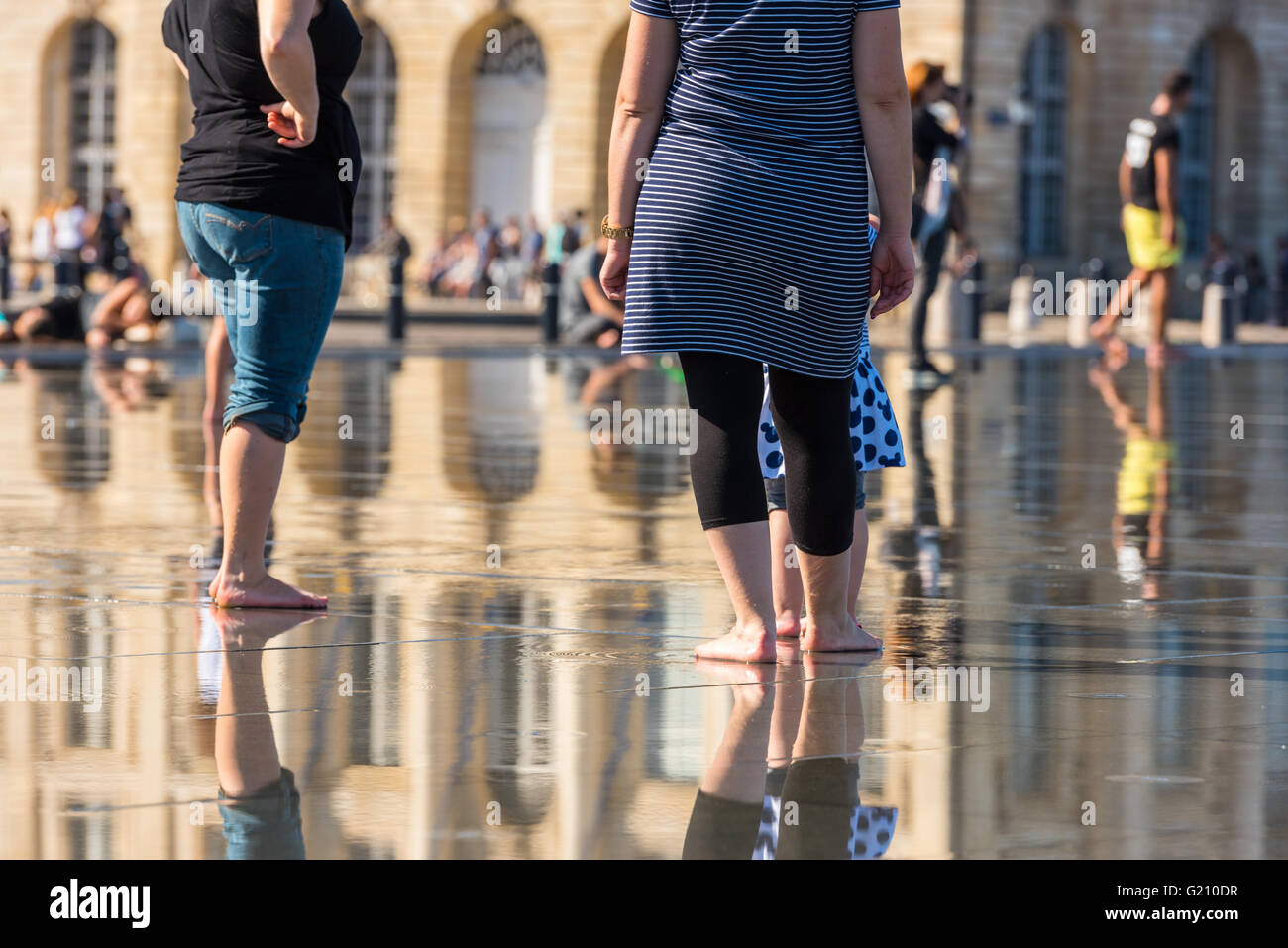 Leute, die Spaß in einem Spiegel-Brunnen vor dem Place De La Bourse in Bordeaux, Frankreich Stockfoto