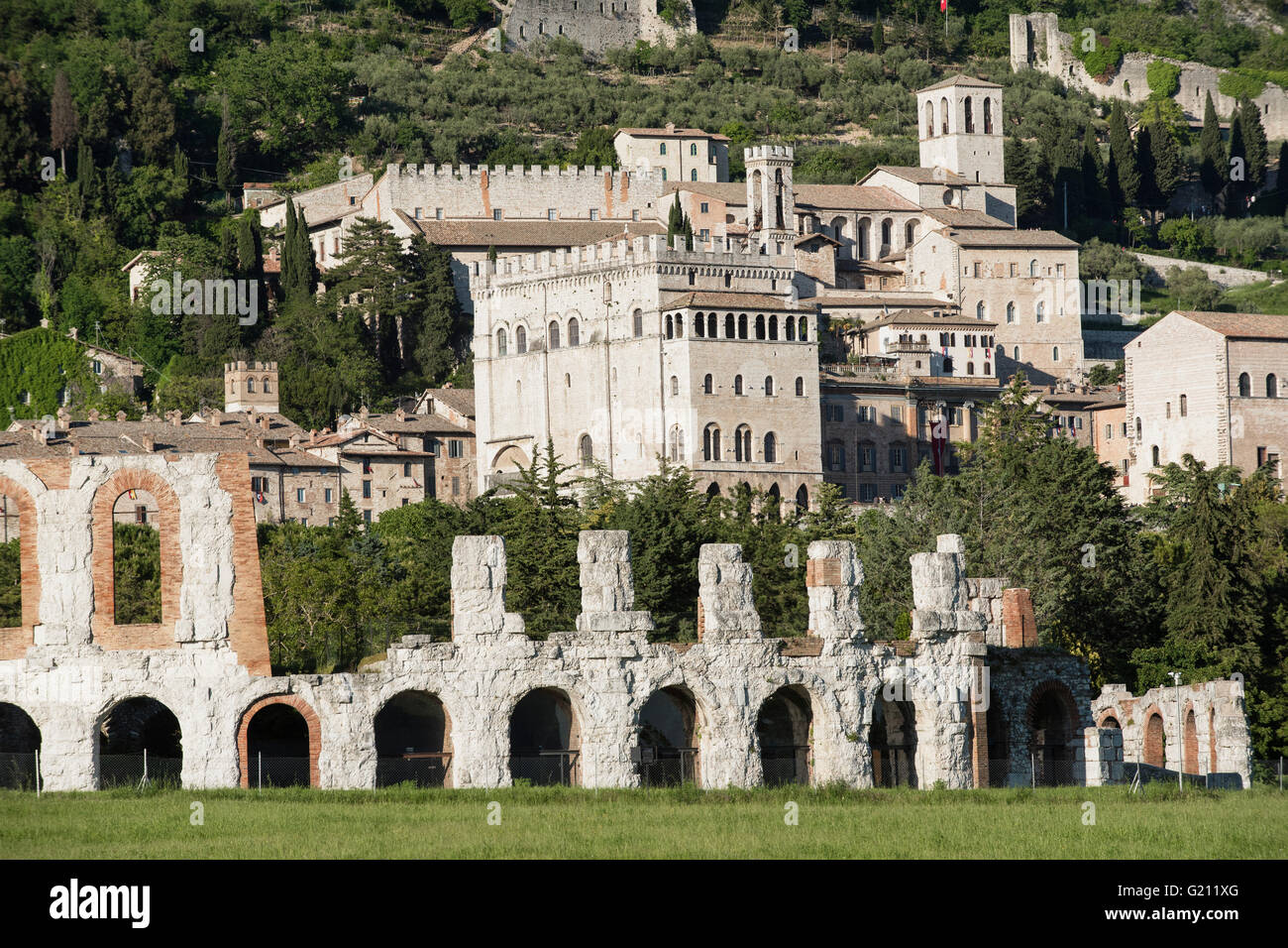 Gubbio, Umbrien. Im Vordergrund, das antike römische Theater. Im Hintergrund die Skyline von der mittelalterlichen Stadt. Stockfoto