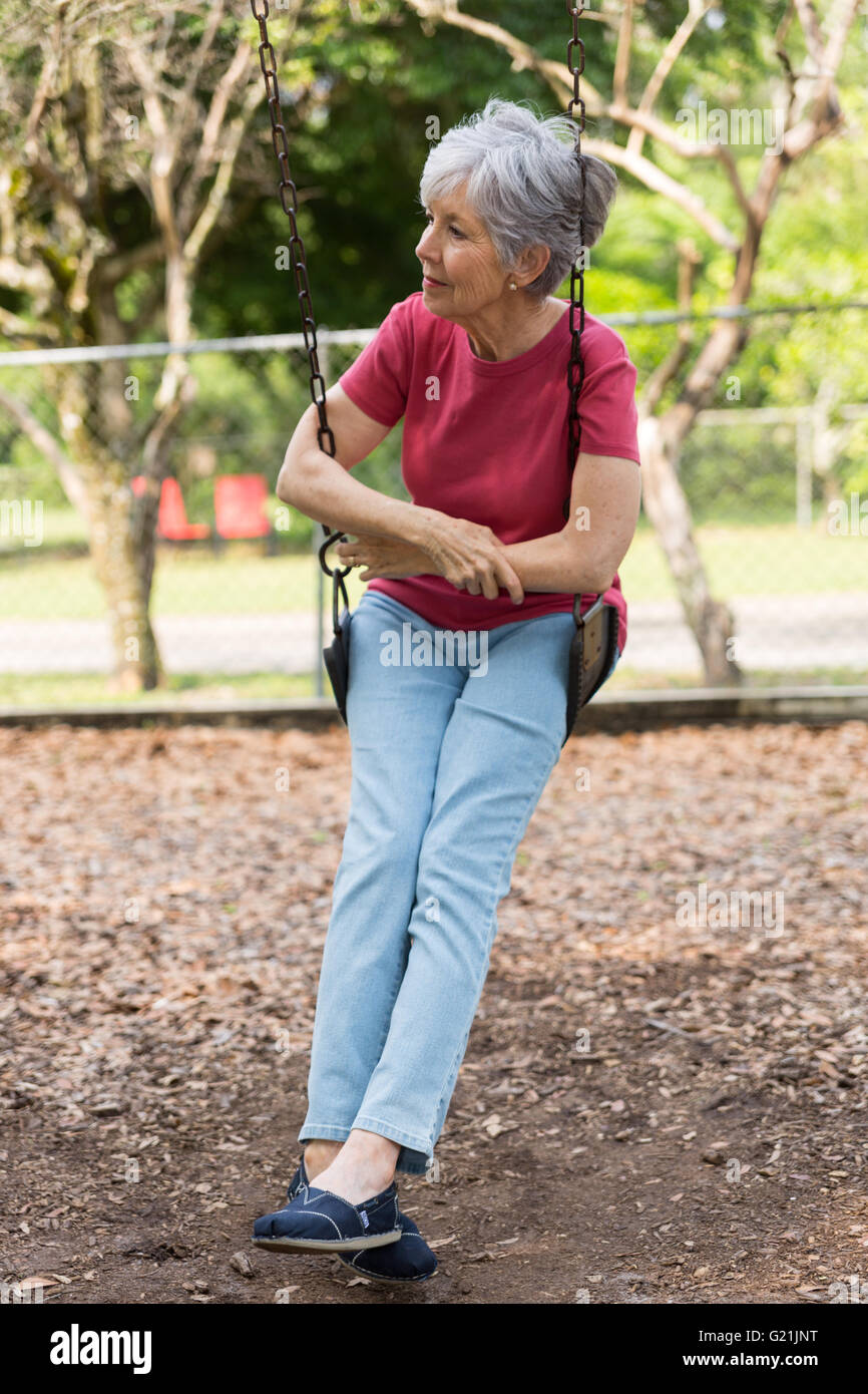 ältere Dame auf einer Schaukel in tiefe Gedanken nachdenken, entspannen Stockfoto